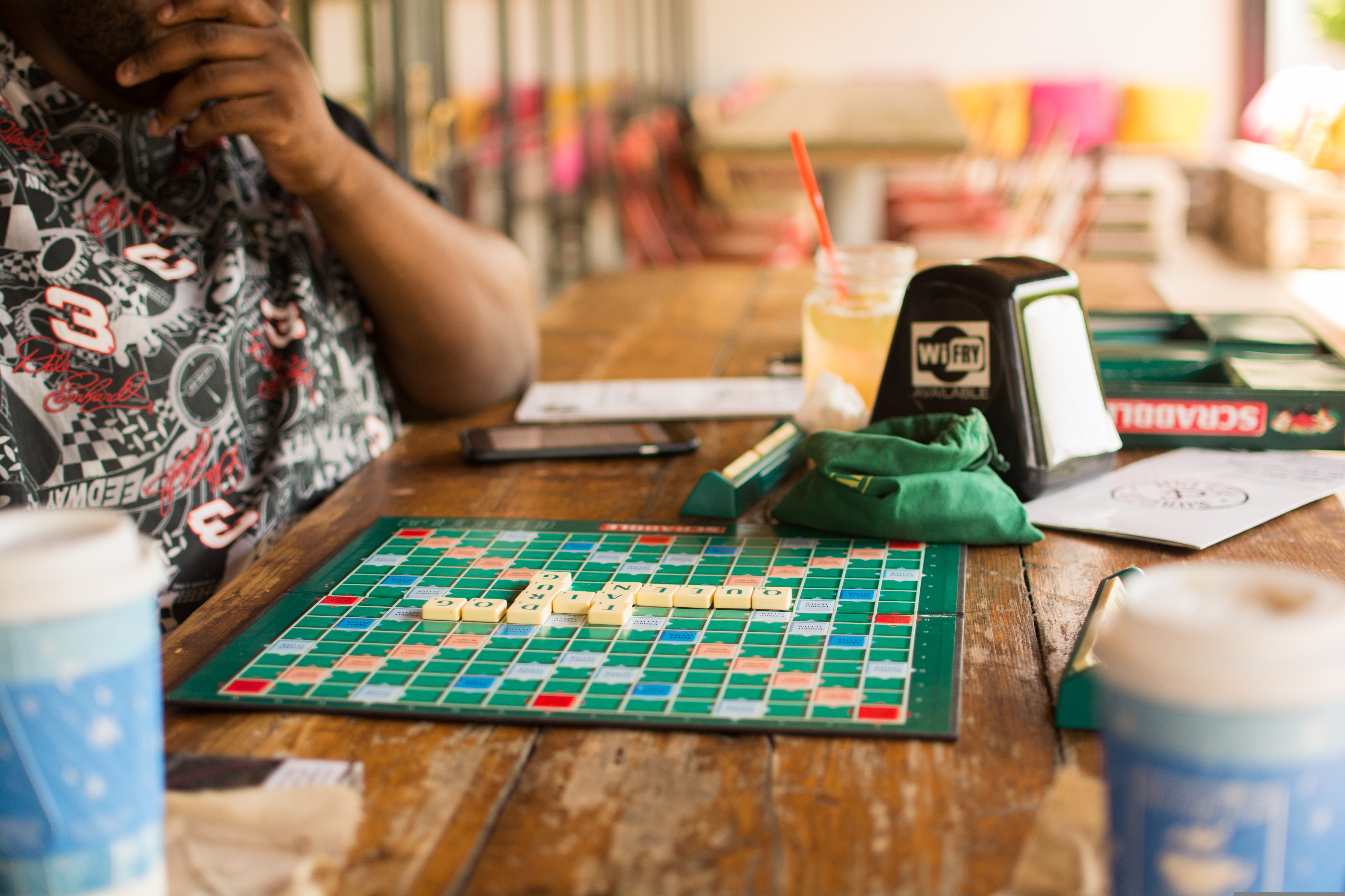 An image of a person playing a word board game at a cafe